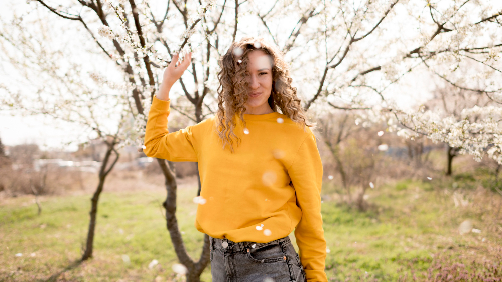 Девушка в желтом свитере на фоне цветущих веток