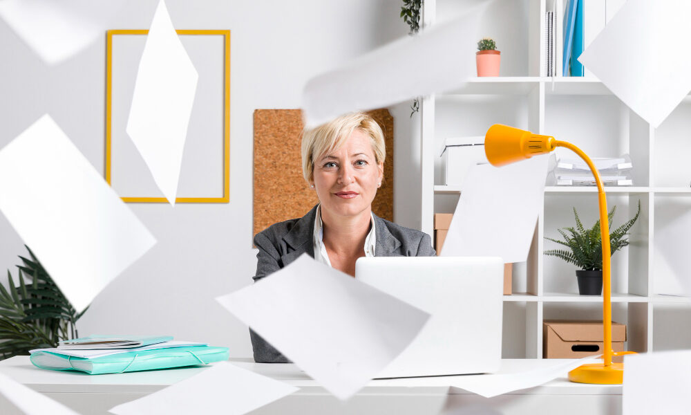 Женщина в офисе сохраняет спокойствие при полном хаосе вокруг.