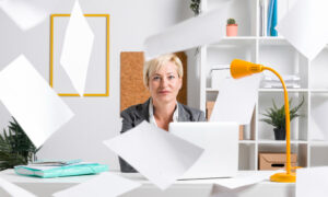 Женщина в офисе сохраняет спокойствие при полном хаосе вокруг.