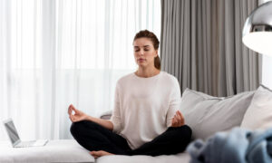 Девушка занимается йогой дома на диване.