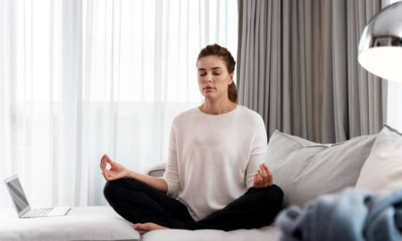 Девушка занимается йогой дома на диване.