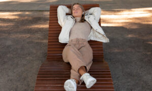 Девушка лежит на деревянном шезлонге в парке,