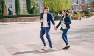 Пара гуляет по площади, держа в руках стаканчики с кофе.