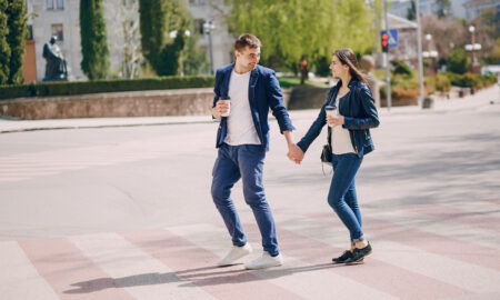 Пара гуляет по площади, держа в руках стаканчики с кофе.