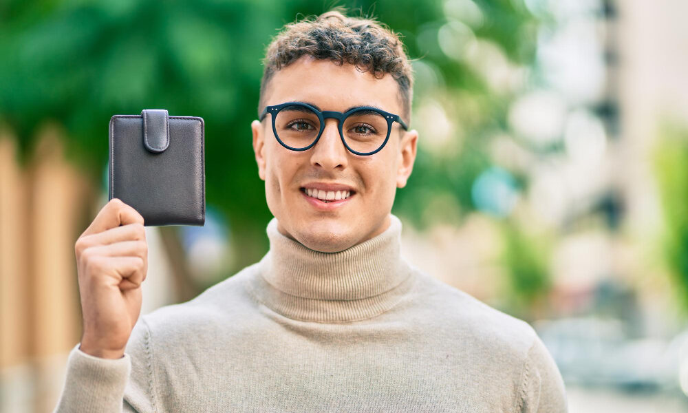 Парень в очках держит в руках портмоне.