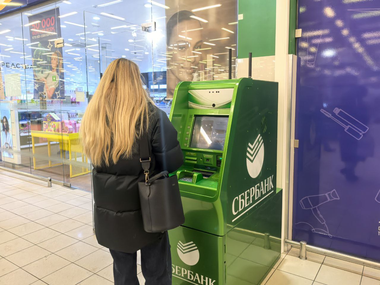 Женщина переводит деньги через банкомат
