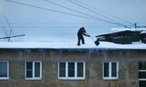 Мужчина сбрасывает снег с крыши