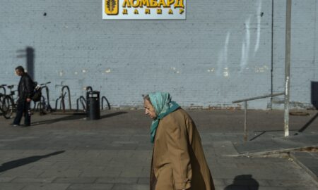 Женщина пенсионного возраста на фоне вывески ломбарда.