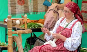 женщина показывает Новогородские ремесла