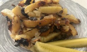 Жаренная картошка с лесными грибами на тарелке.