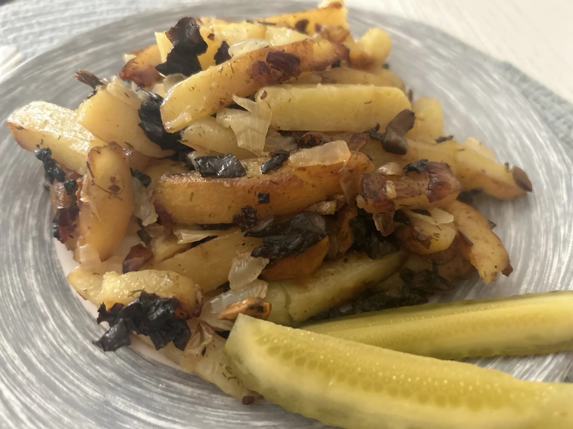 Жаренная картошка с лесными грибами на тарелке.