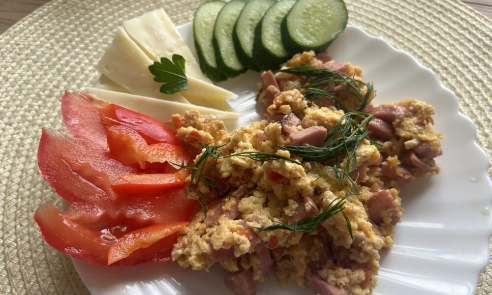 Скрембл с колбасой и овощами на тарелке.