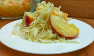 квашенная капуста с яблоками на тарелке.